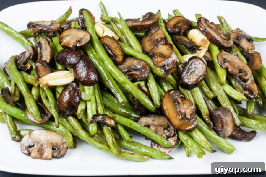 A vibrant platter of perfectly roasted green beans and crimini mushrooms, seasoned and ready to serve.