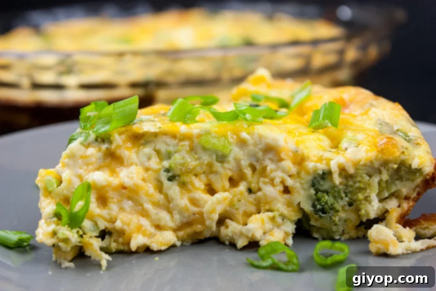 Slice of crustless broccoli cheddar quiche on gray plate garnished with diced green onions.