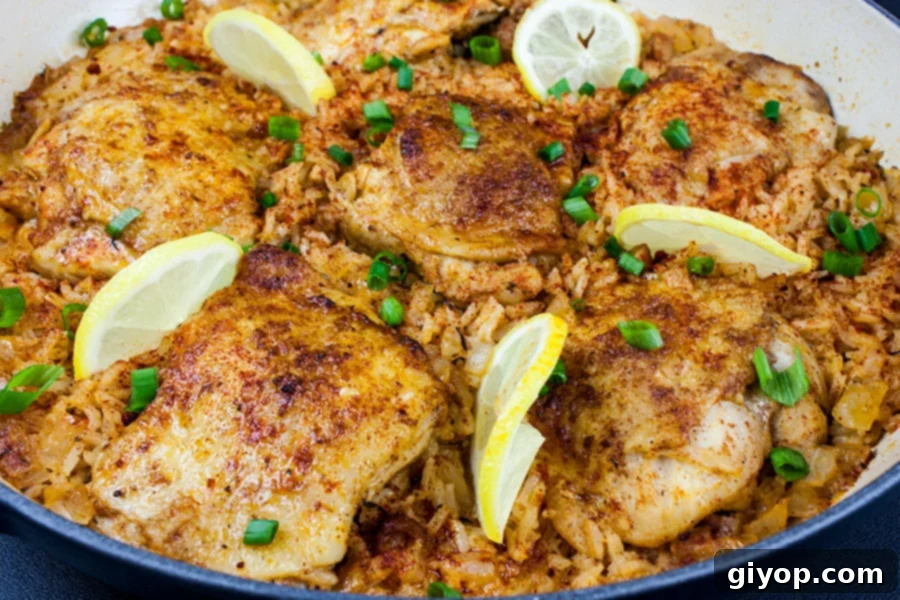 A vibrant One Pan Spanish Chicken and Rice in a skillet, garnished with fresh lemon slices and chopped green onions.