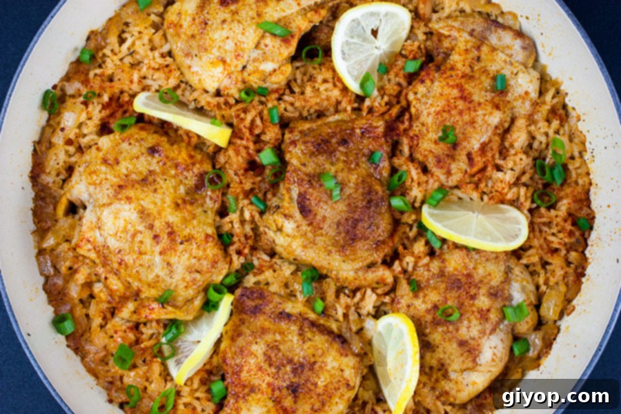 Close-up of cooked One Pan Spanish chicken and rice, beautifully arranged in the skillet with lemon slices and green onions.