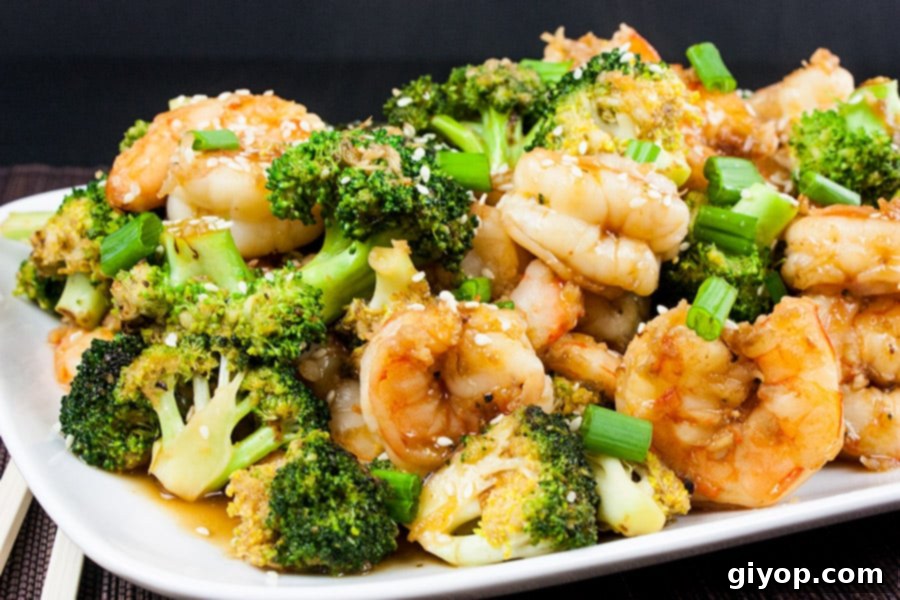 Savory Sesame Shrimp and Broccoli 2 Shrimp and Broccoli Stir Fry on a white serving dish, garnished with sesame seeds and green onions.