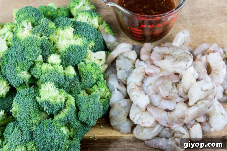 Savory Sesame Shrimp and Broccoli 3 Shrimp and Broccoli Stir Fry - raw shrimp, chopped broccoli, and sauce mixture on a cutting board, ready for cooking.