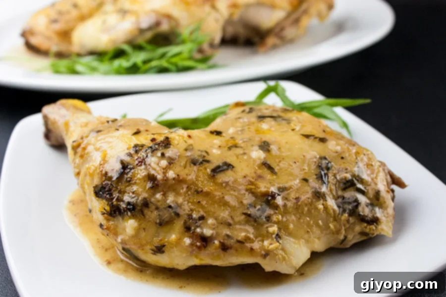 Roasted Chicken with a Dijon Cream Sauce on a white plate garnished with fresh tarragon.