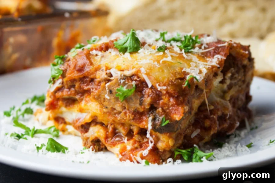 Lasagna on a white plate garnished with parsley and cheese, ready to be served.