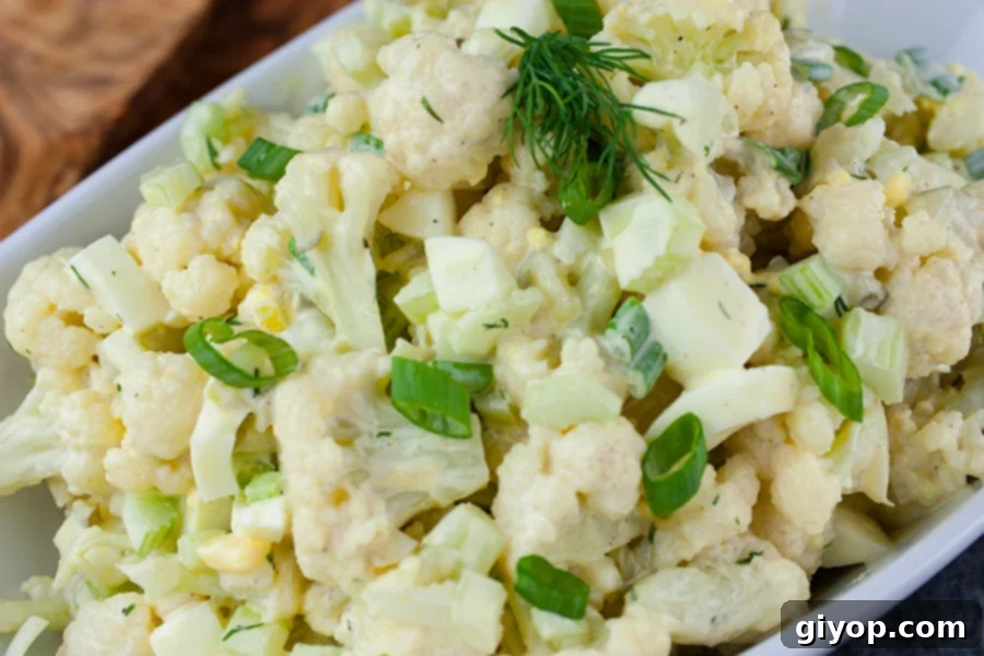 Clever Cauliflower Potato Salad 2 Cauliflower Mock Potato Salad in a white serving dish, garnished with fresh herbs.