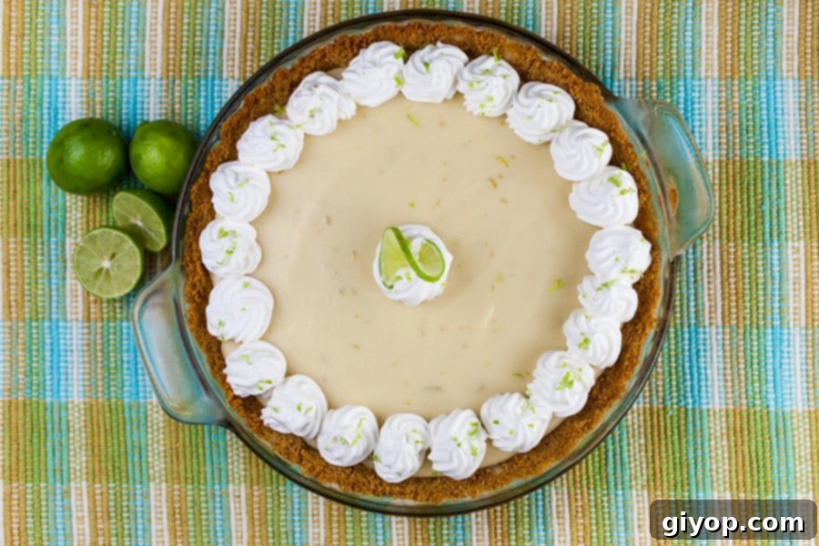 A freshly baked Key Lime Pie, adorned with a luxurious swirl of whipped cream and a delicate slice of fresh lime, ready to be served. The bright colors promise a refreshing and tangy treat.