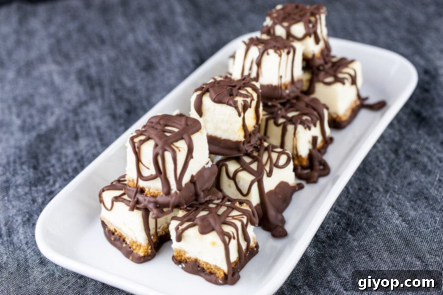 Chocolate Covered Cheesecake Bites - cheesecake bites neatly stacked on a white platter, ready for serving.