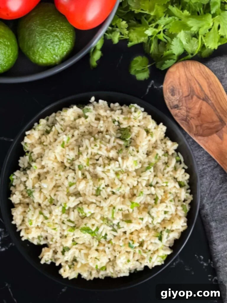 Freshly prepared cilantro lime rice in a dark bowl on a rustic dark surface, ready to be served.