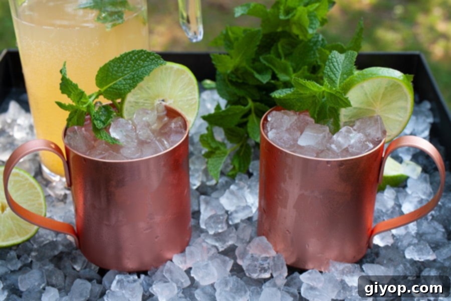 Skinny Moscow mules in copper mugs on a tray of ice garnished with fresh mint.