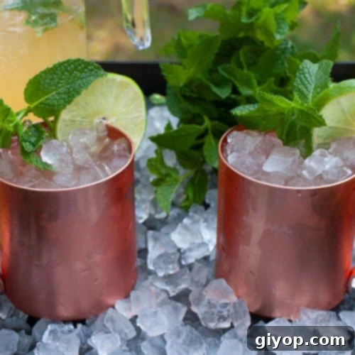 Skinny Moscow mules in copper mugs on a tray of ice garnished with fresh mint.
