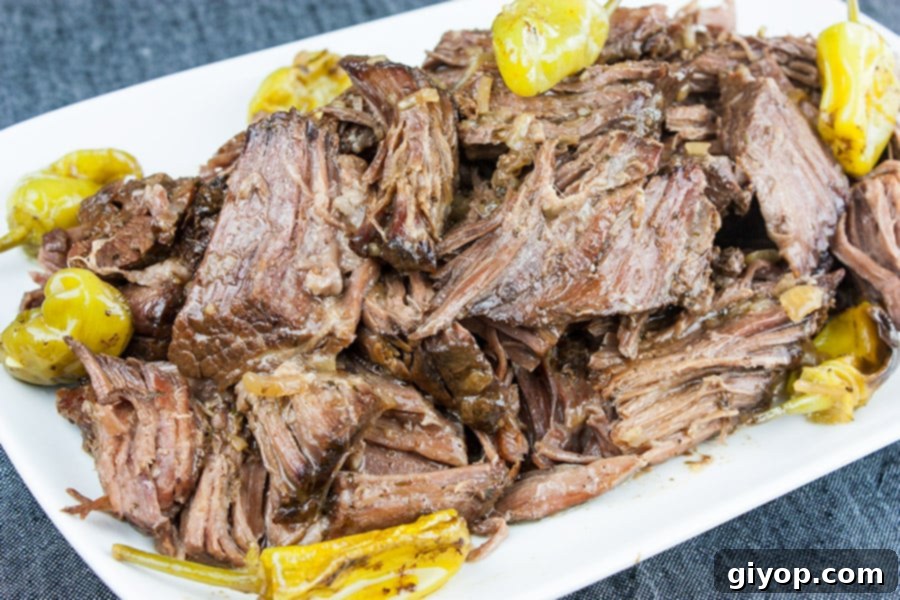 Melt-in-Your-Mouth Mississippi Pot Roast 4 Cooked, tender Mississippi Pot Roast on a white serving platter, garnished with fresh parsley and whole pepperoncini peppers.