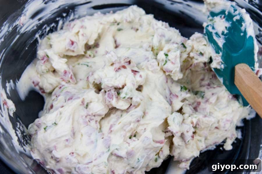 All the essential ingredients for making the cheese ball, including cream cheese, pastrami, green onions, and spices, neatly arranged in a clear mixing bowl.