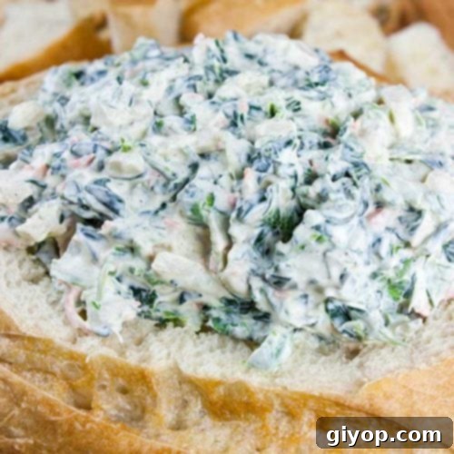 Easy spinach dip in a bread bowl surrounded by bread cubes.
