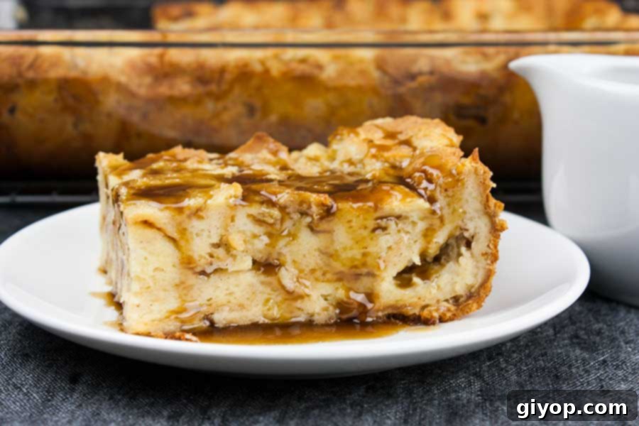 Bourbon Kissed Bread Pudding 2 A slice of bread pudding on a white plate drizzled with bourbon sauce.