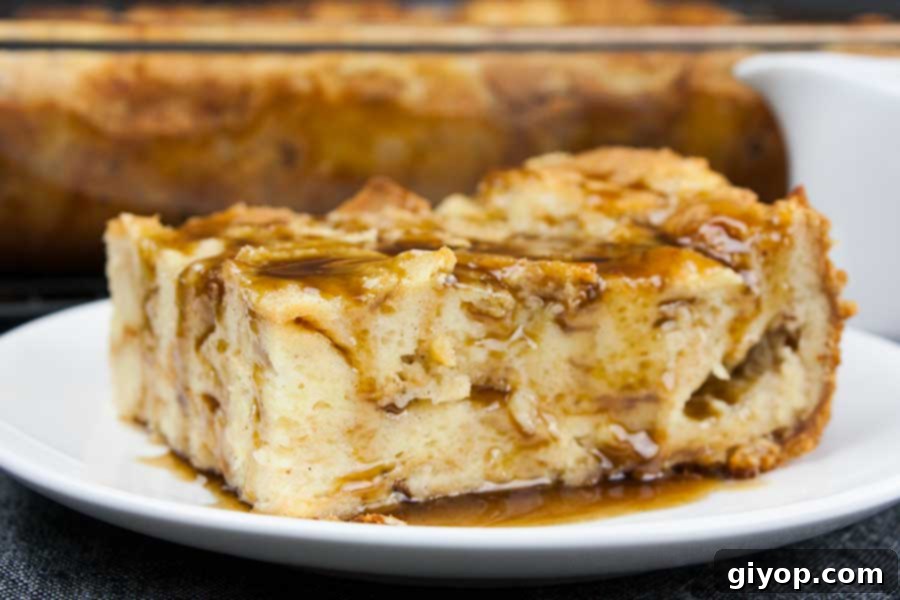Bourbon Kissed Bread Pudding 9 Slice of bread pudding with bourbon sauce poured over the top on a white plate.