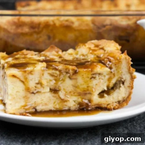 Bourbon Kissed Bread Pudding 13 A slice of bread pudding on a white plate drizzled with bourbon sauce.