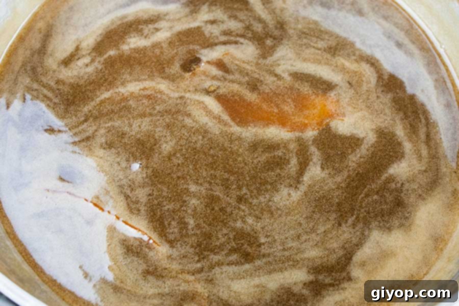 Bread Pudding with Bourbon Sauce - Moist, dense yet light, kissed with classic spice flavor. This bread pudding is decadence at it's best! The bourbon sauce makes it over-the-top indulgent! Bourbon sauce in sauce pan.