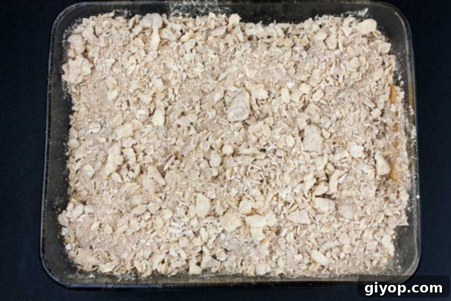 Apples and topping in a glass baking dish.