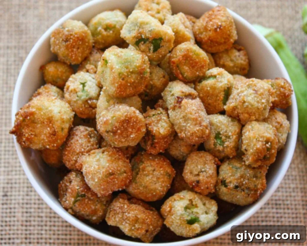 A generous serving of golden-brown buttermilk fried okra resting in a rustic white bowl, ready to be enjoyed as a classic Southern side dish.