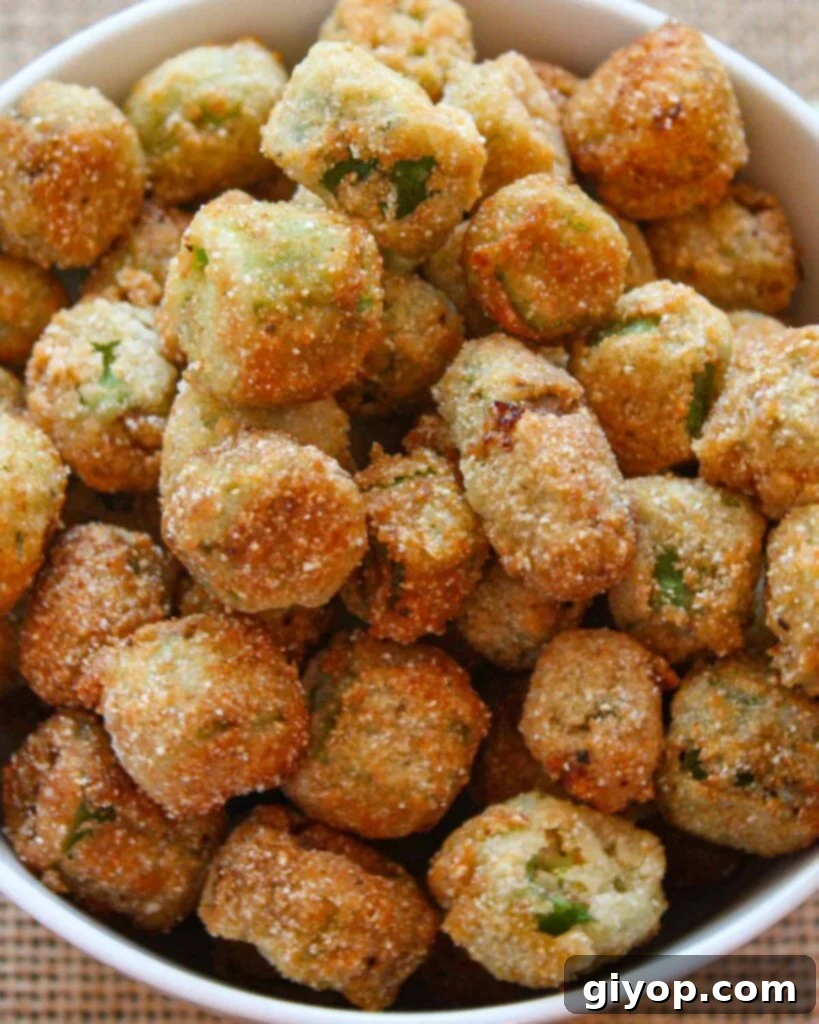 A close-up shot of perfectly fried okra in a white serving bowl, highlighting its golden crispiness and inviting texture, a true Southern comfort food.