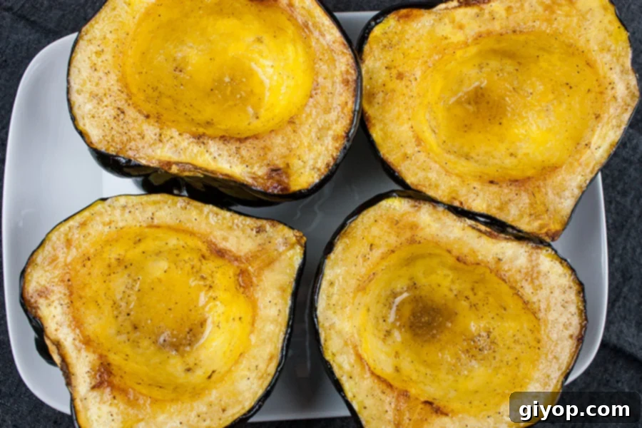 Perfectly Roasted Acorn Squash Recipe 4 Golden brown roasted acorn squash halves resting on a white platter, beautifully cooked and tender, ready for serving.