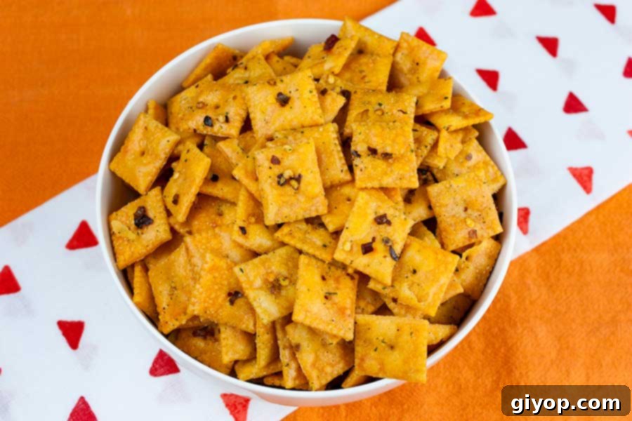 A white bowl filled with Firecracker Cheez-Itz, perfectly seasoned and ready to eat, resting on a vibrant orange tablecloth.