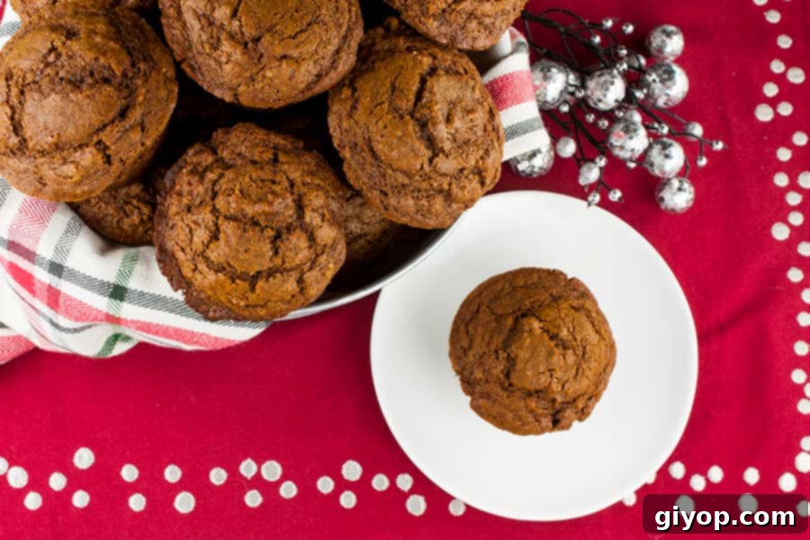 Gingerbread muffins artfully arranged in a rustic basket, nestled on a red, white, and green holiday towel, evoking a festive atmosphere.