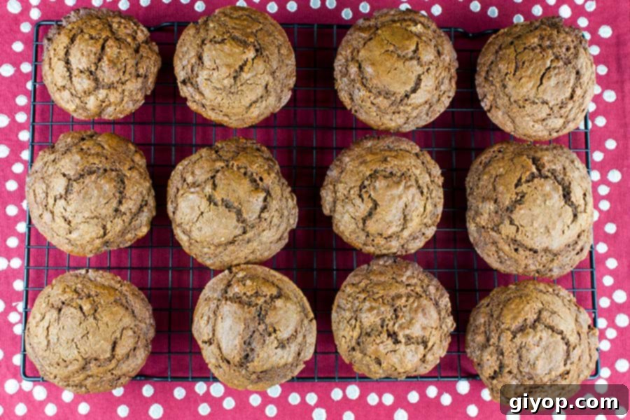Freshly baked gingerbread muffins cooling on a wire rack, showcasing their beautifully cracked tops and golden-brown hue.