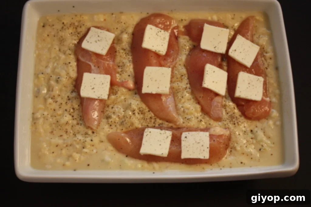 Golden Chicken and Rice Bake 3 Ingredients in a white casserole dish before baking, showing raw chicken breasts on a bed of rice and soup mixture.