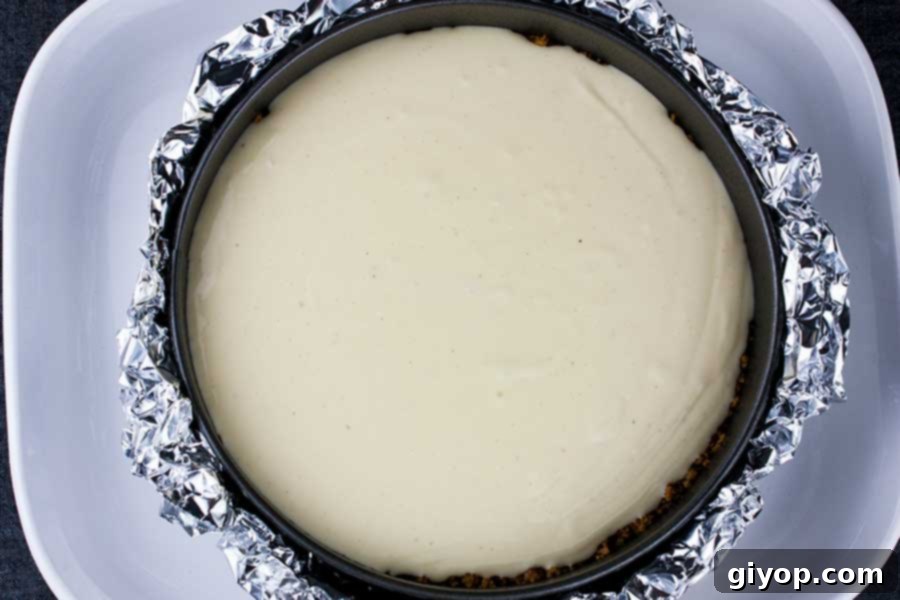 Unbaked eggnog cheesecake batter in a springform pan, nestled within a water bath, ready for baking.