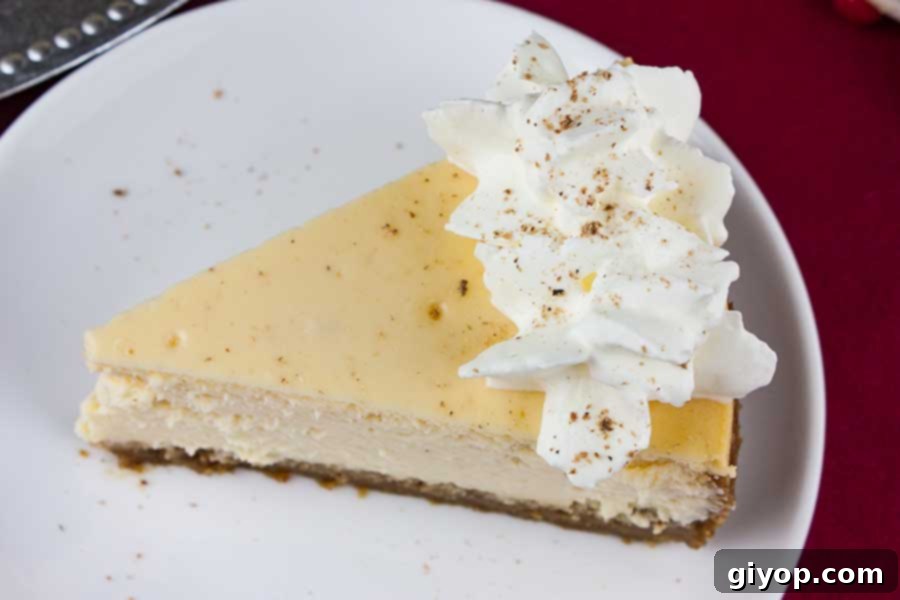 A generous slice of eggnog cheesecake, highlighting its smooth, creamy interior and inviting golden-brown gingersnap crust.
