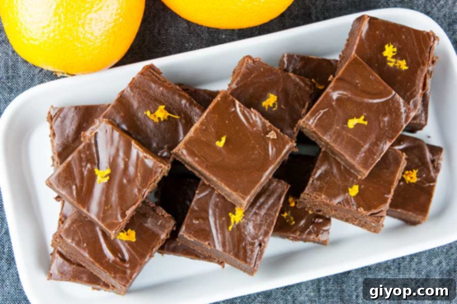 Chocolate orange fudge squares arranged elegantly on a white rectangle platter, adorned with delicate orange zest curls.