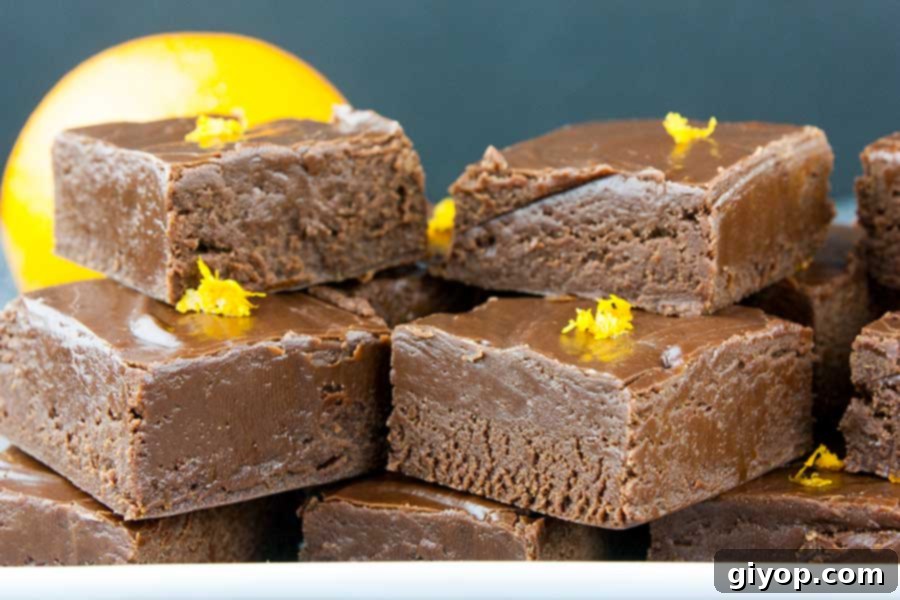 Close-up view of chocolate orange fudge squares, each delicately garnished with orange zest, showcasing its rich texture and appetizing appeal.