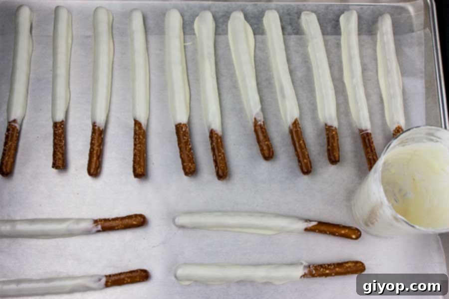 White Chocolate Covered Pretzel Rods on a parchment paper lined baking sheet.