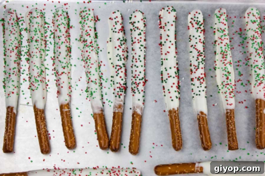 White Chocolate Covered Pretzel Rods on a parchment lined baking sheet.