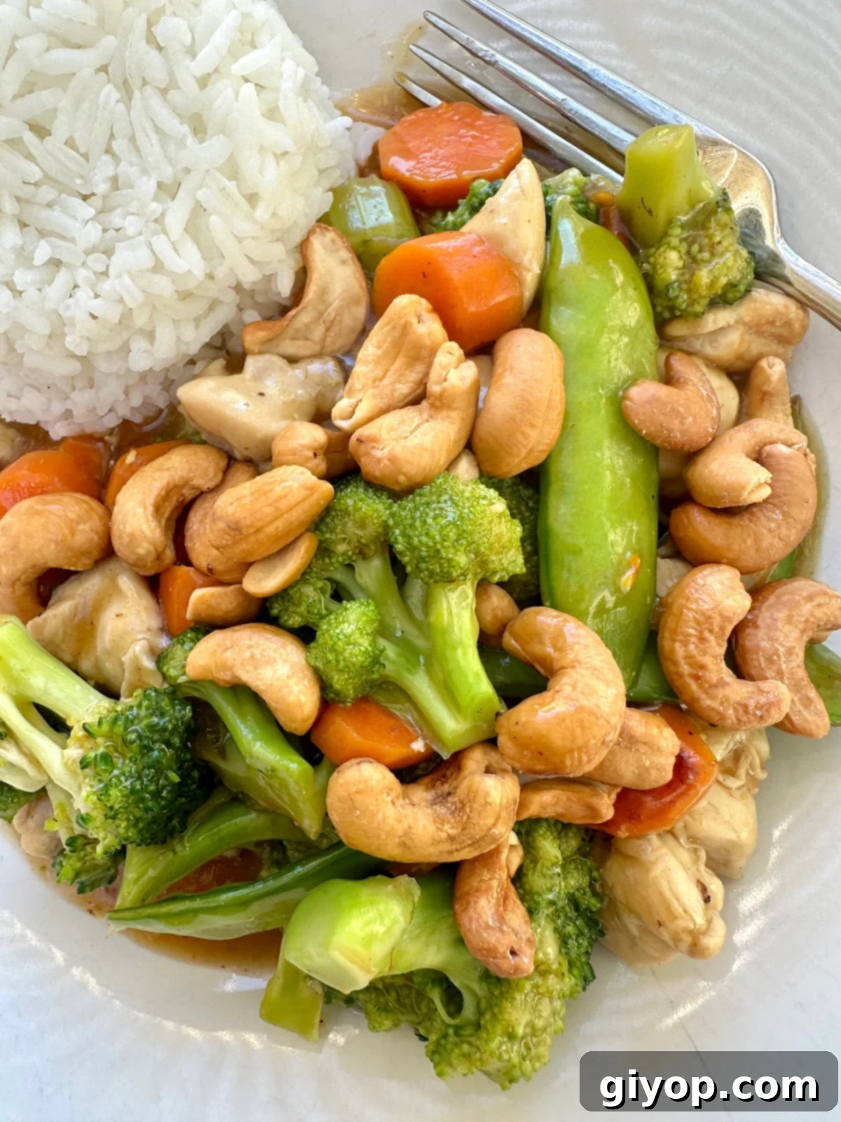 Chicken stir fry with cashews on a plate with rice.