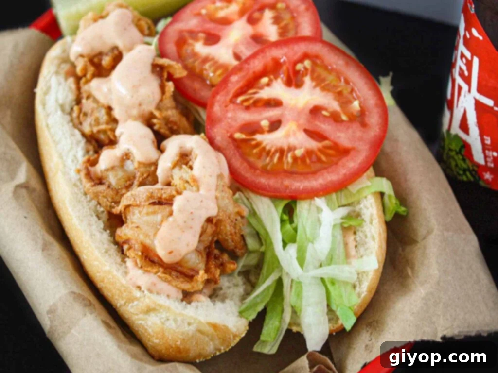 Shrimp po'boy in a brown paper-lined red basket, showcasing its crispy texture and vibrant fillings.