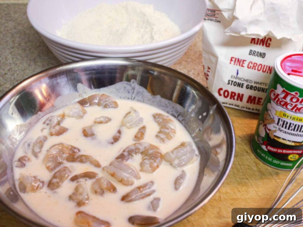 Raw shrimp soaking in a buttermilk and Creole seasoning mixture, ready for dredging.