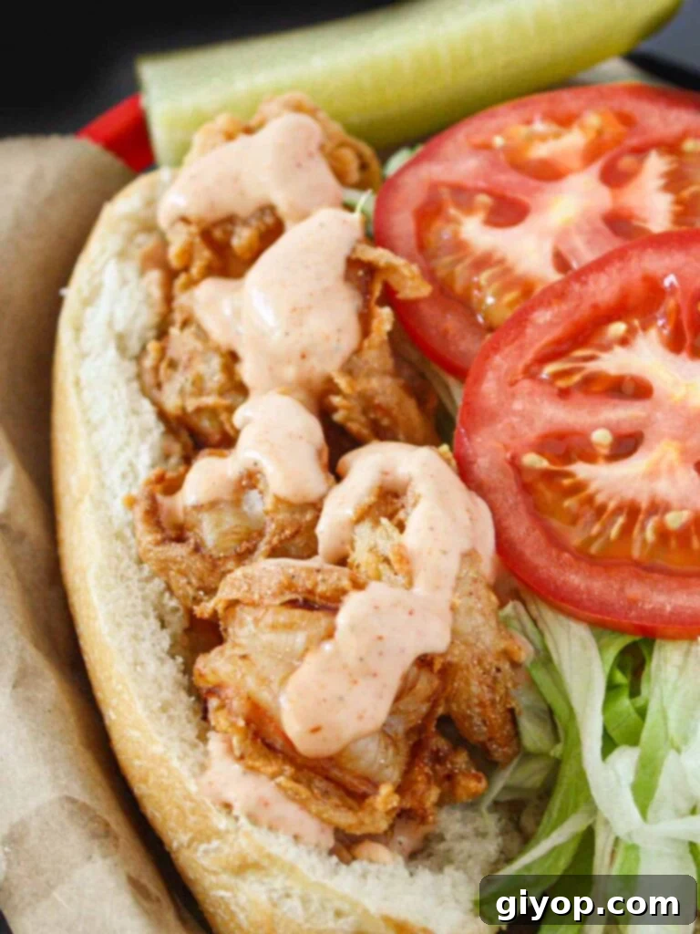 A fully assembled Shrimp Po' Boy sandwich, brimming with crispy shrimp, fresh vegetables, and sauce, presented beautifully in a brown paper-lined red basket.