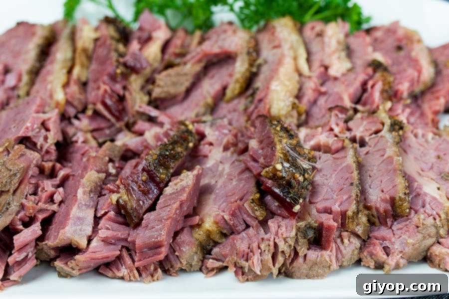 Melt-in-Your-Mouth Slow Cooker Corned Beef 2 Slow cooker corned beef on a white plate garnished with parsley.