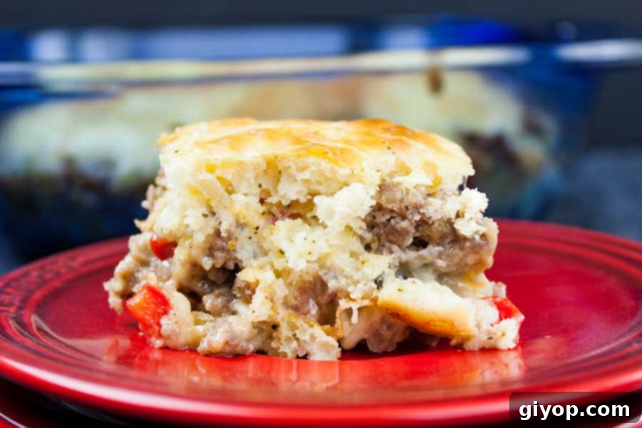 A slice of delicious Sausage Breakfast Cake, golden brown and cheesy, served on a vibrant red plate, ready to be enjoyed.