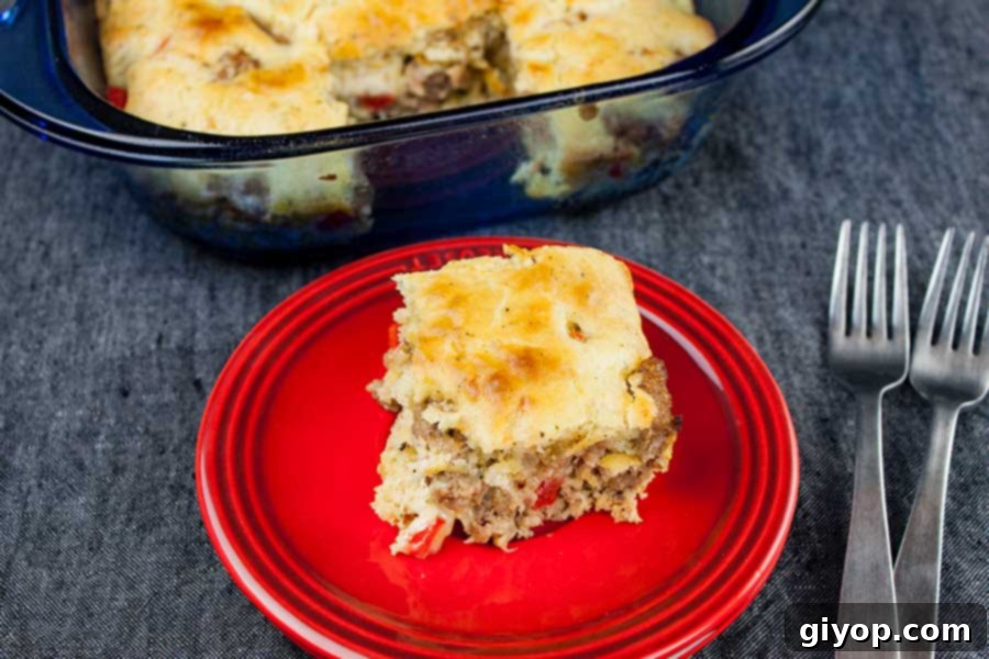 A perfectly baked, golden-brown slice of Sausage Breakfast Cake, bursting with savory goodness, presented elegantly on a bright red plate.