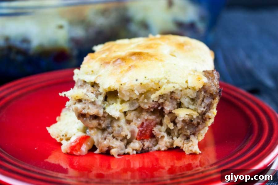 Another enticing view of a slice of the golden-brown Sausage Breakfast Cake on a red plate, showcasing its savory layers and appealing texture.