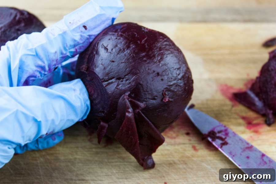 A gloved hand expertly holds a warm, cooked beet, using a paring knife to gently remove the skin, showcasing the ease of peeling after pressure cooking.