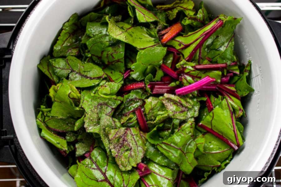 beet greens in the pot of the Ninja Foodi seasoned with salt and pepper