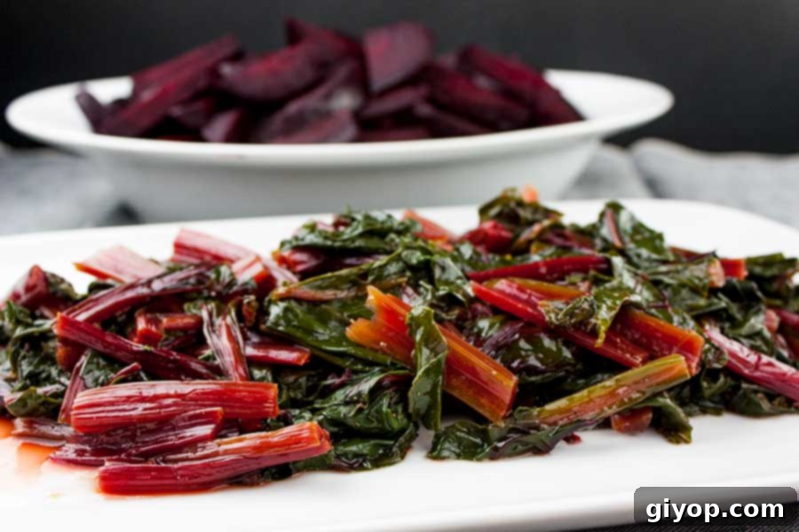 cooked Fresh Beet Greens  on a white platter with cooked beets in a white serving platter in the background