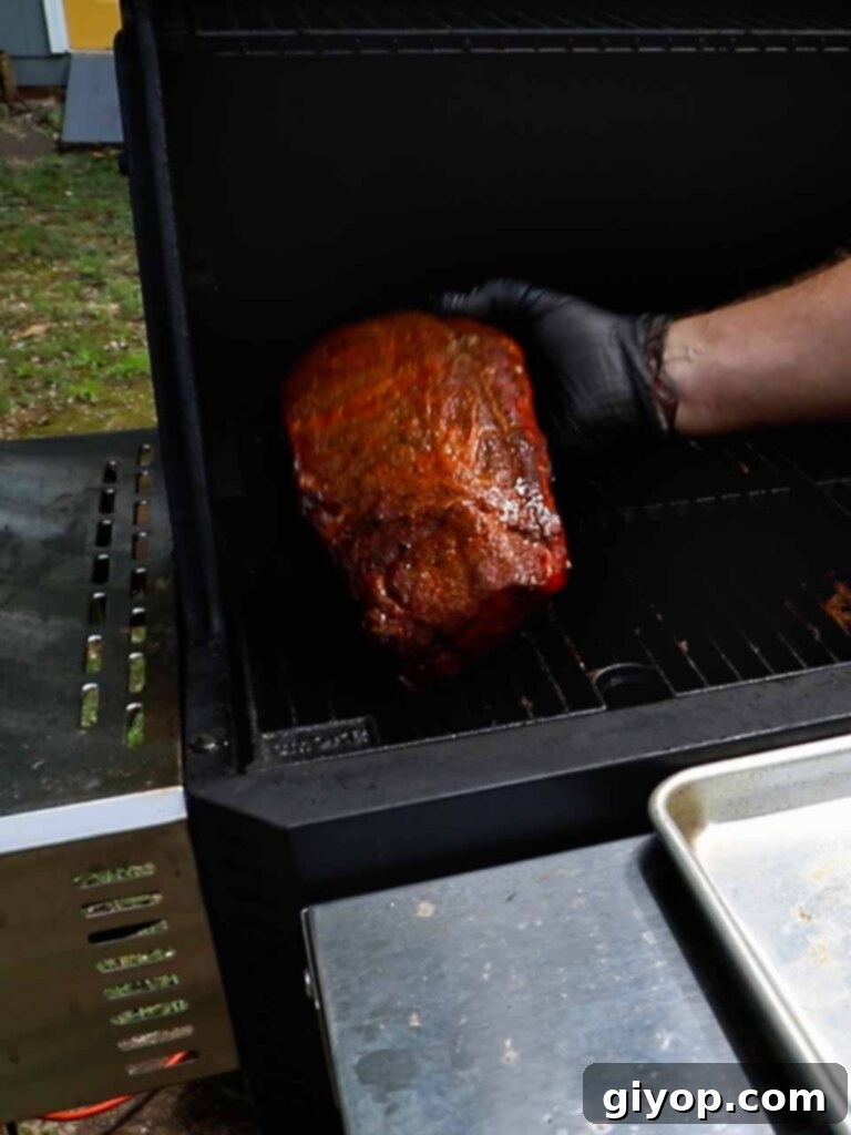 A hand performing the 'rib bend test' on a rack of smoked baby back ribs, lifting them to check for flexibility and doneness.