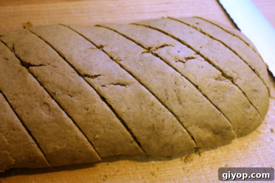 Autumn Spice Latte Biscotti 4 Freshly baked pumpkin spice biscotti logs, perfectly golden brown and sliced into individual pieces on a rustic wooden cutting board.