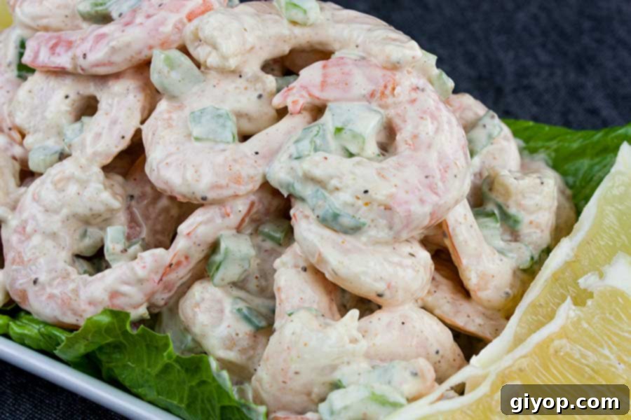 Delicious creamy shrimp salad served over crisp lettuce leaves in an elegant white bowl, perfect for a refreshing meal.