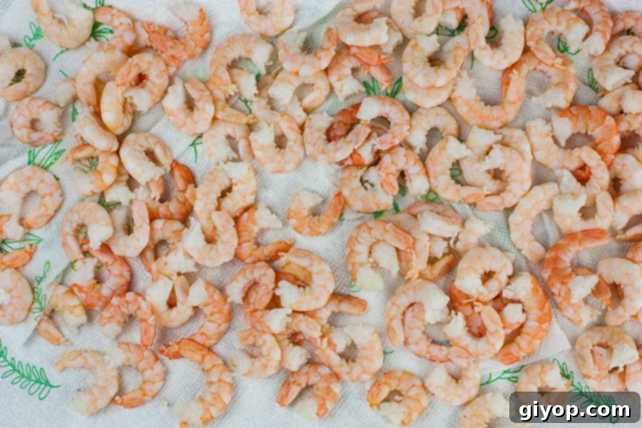 Frozen shrimp being thawed on paper towels, ensuring optimal texture for the salad.